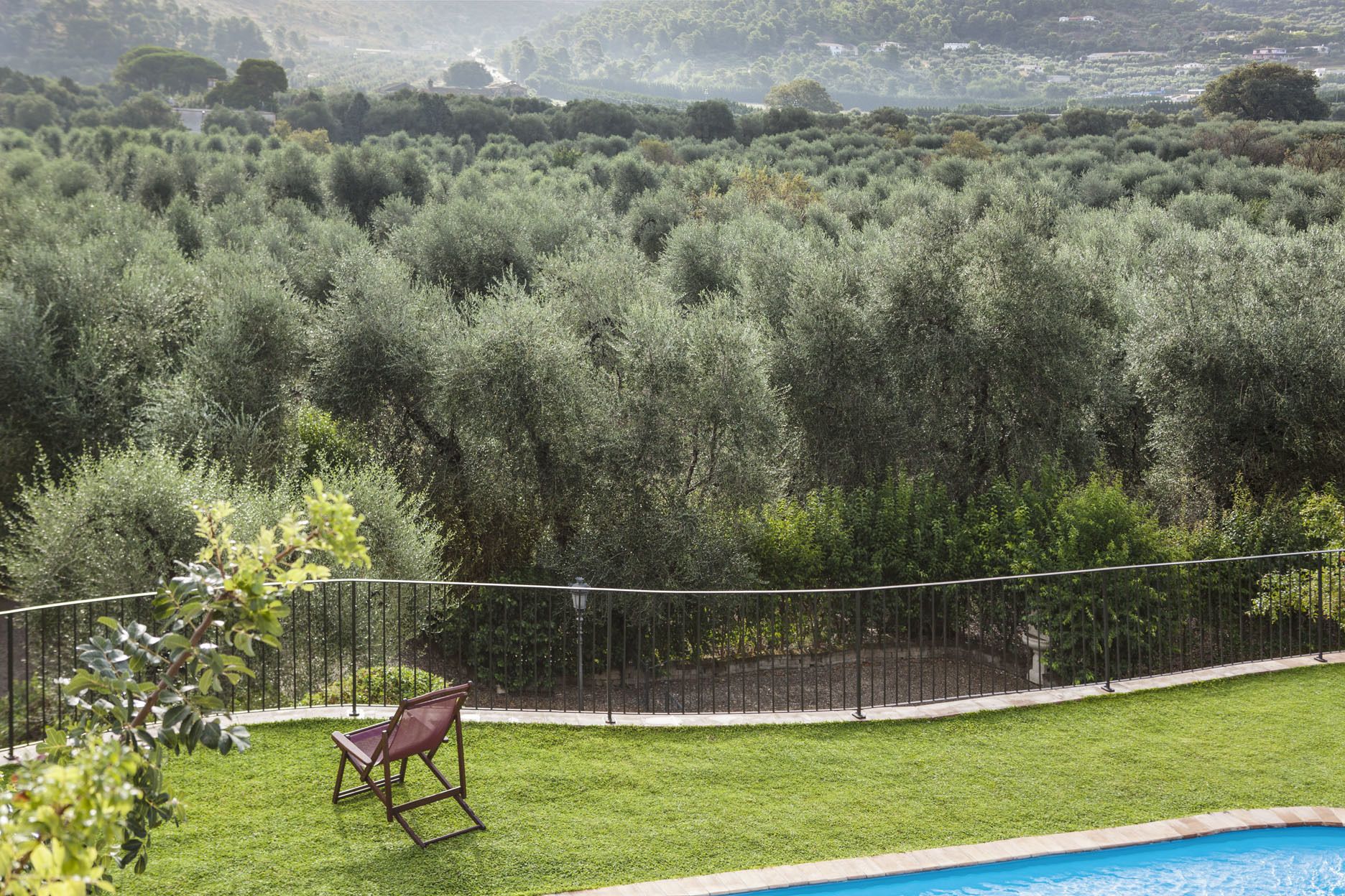 A pool area with a chair and a fence.