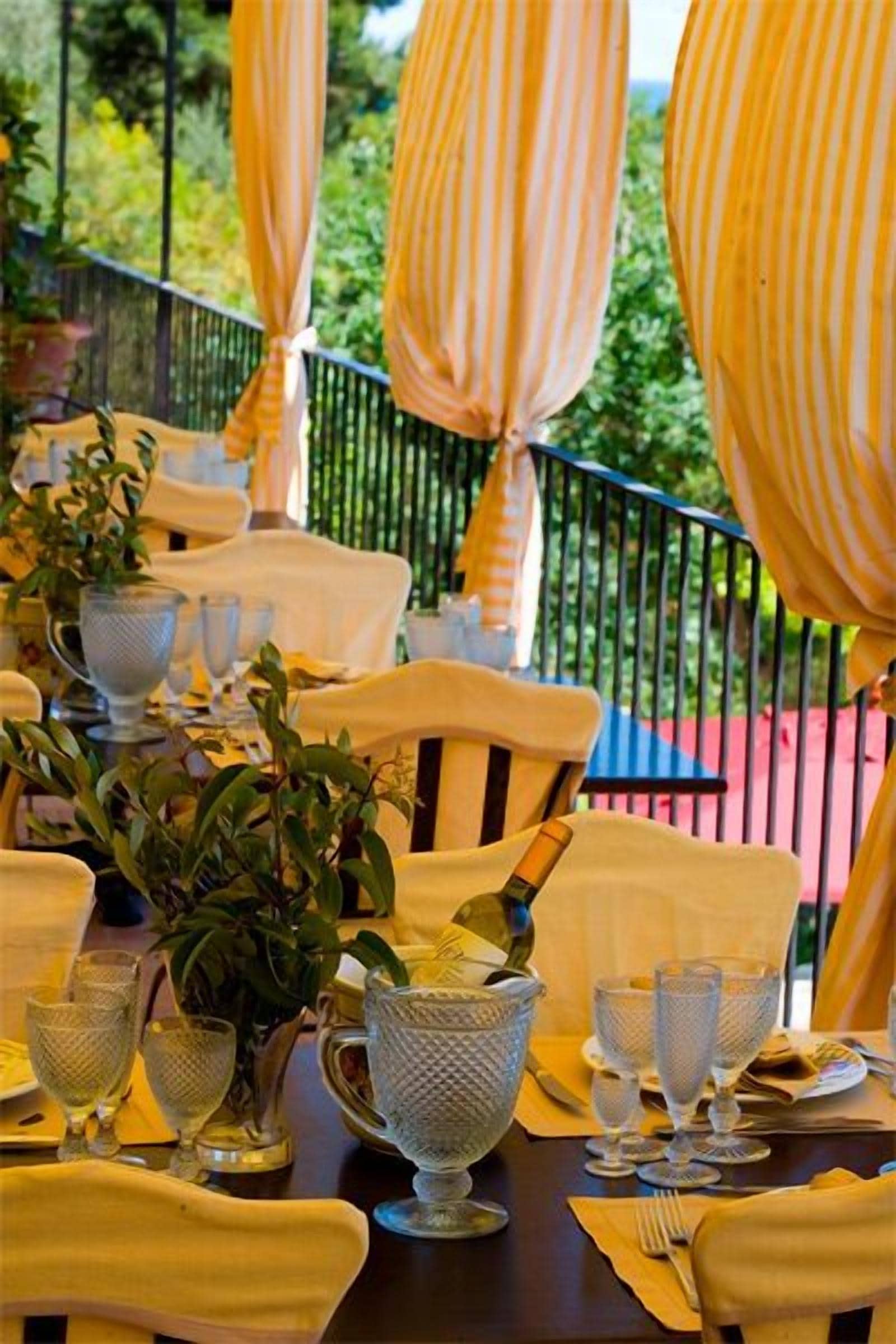 An outdoor dining area with yellow-striped umbrellas, white tablecloths, and glassware.