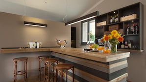 A modern kitchen with a central island, bar stools, and a wine and cocktail bar. - Poste del Chiugi (Castiglione del Lago)