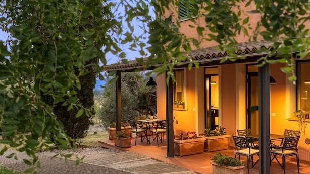 An outdoor patio with a dining area, potted plants, and a pergola. - Poste del Chiugi (Castiglione del Lago)