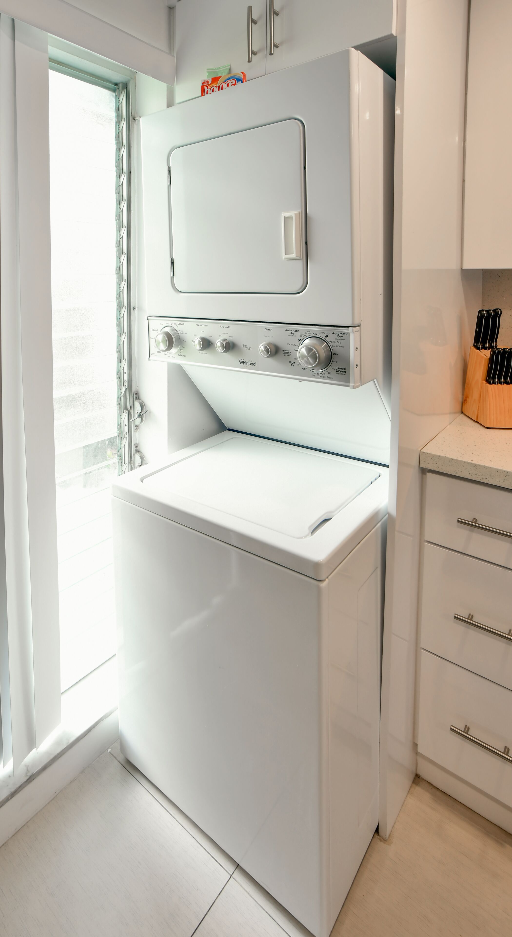 Una cocina compacta con lavadora y secadora integradas, una encimera de madera y un bloque para cuchillos.