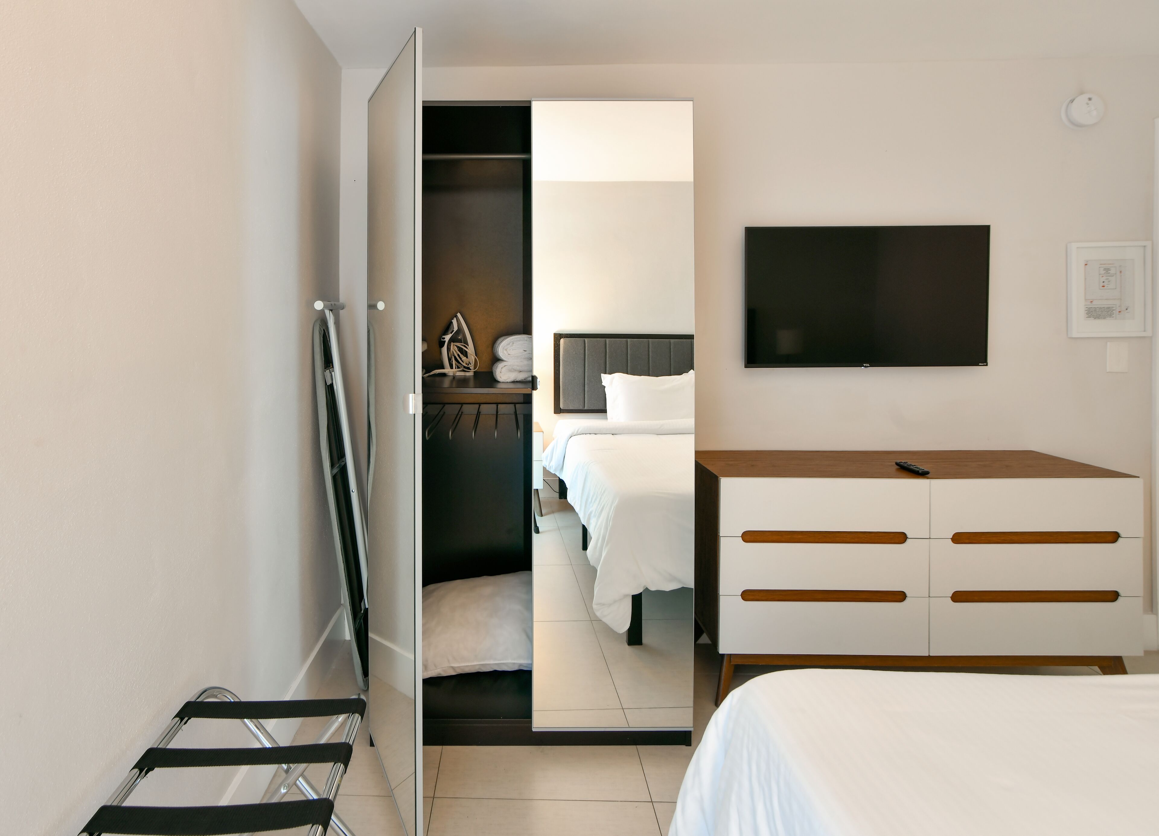 A modern hotel room with a bed, a desk, a TV, and a wardrobe.