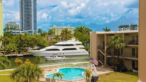 Un grand yacht était amarré près d’une piscine, avec en arrière-plan la vue d’un grand immeuble.