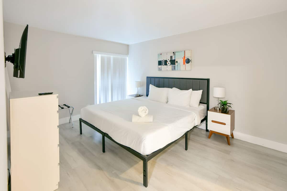A modern bedroom with a bed, bedside table, and a wall-mounted TV.