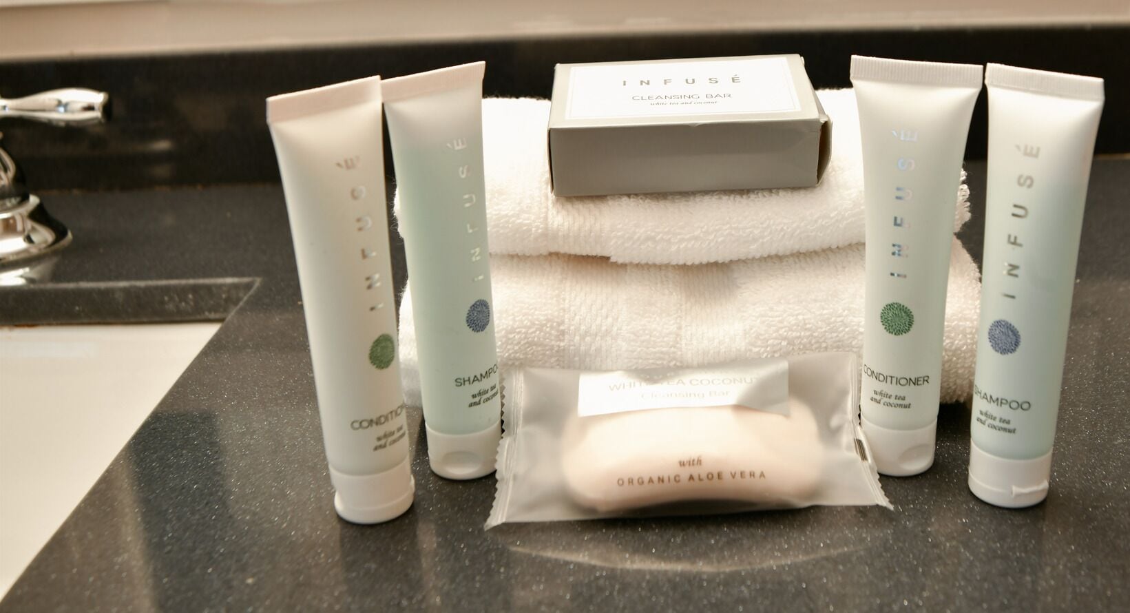 A bathroom counter with various toiletries including a cleansing bar, conditioner, and shampoo.