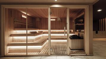 Una sauna con bancos de madera y suelo de baldosas, con una puerta de cristal y una luz en el techo.