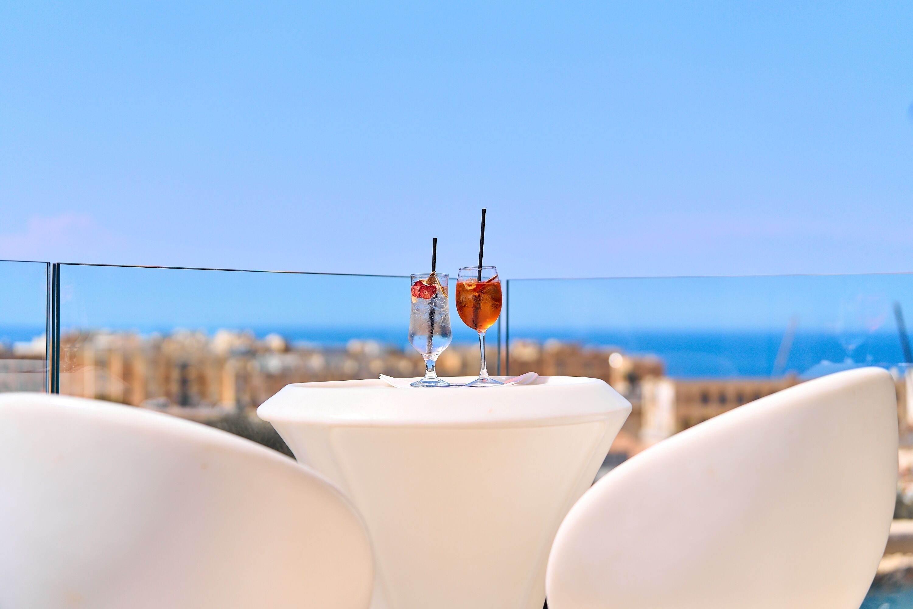 A table with two drinks and a view of the sea.
