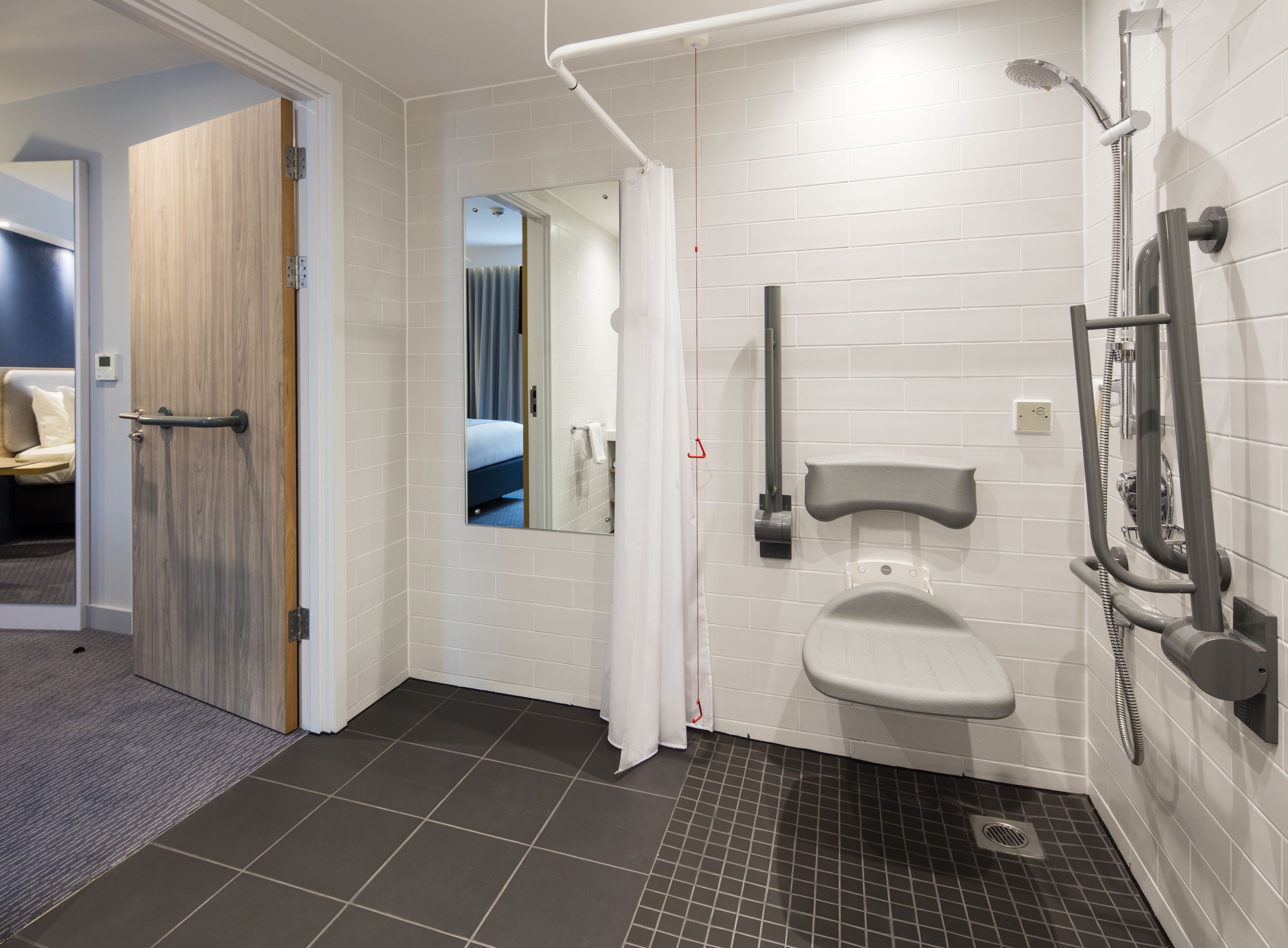 Un baño moderno con ducha, inodoro y espejo.