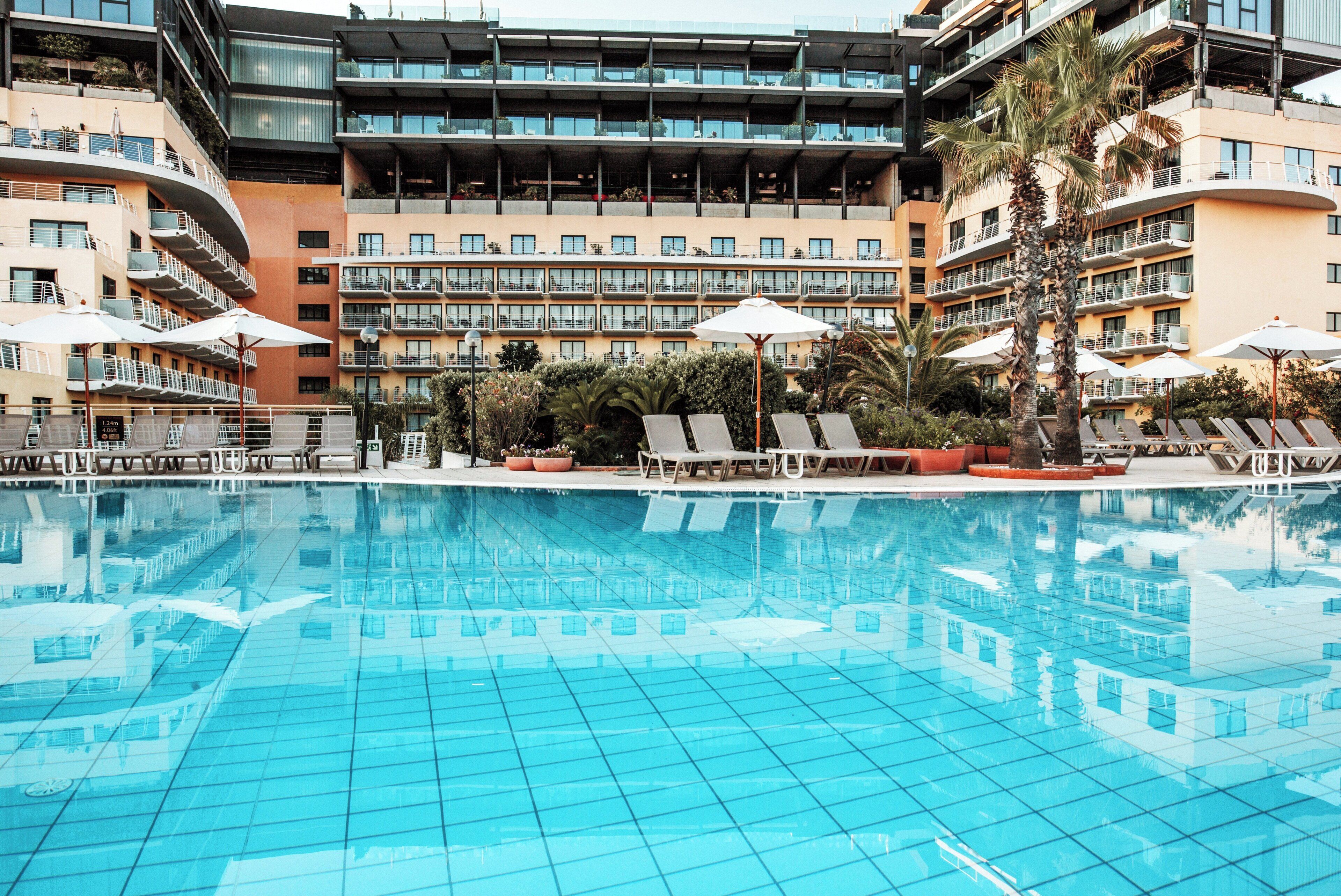 Un hôtel doté d’une piscine, de plusieurs balcons et de chaises longues.