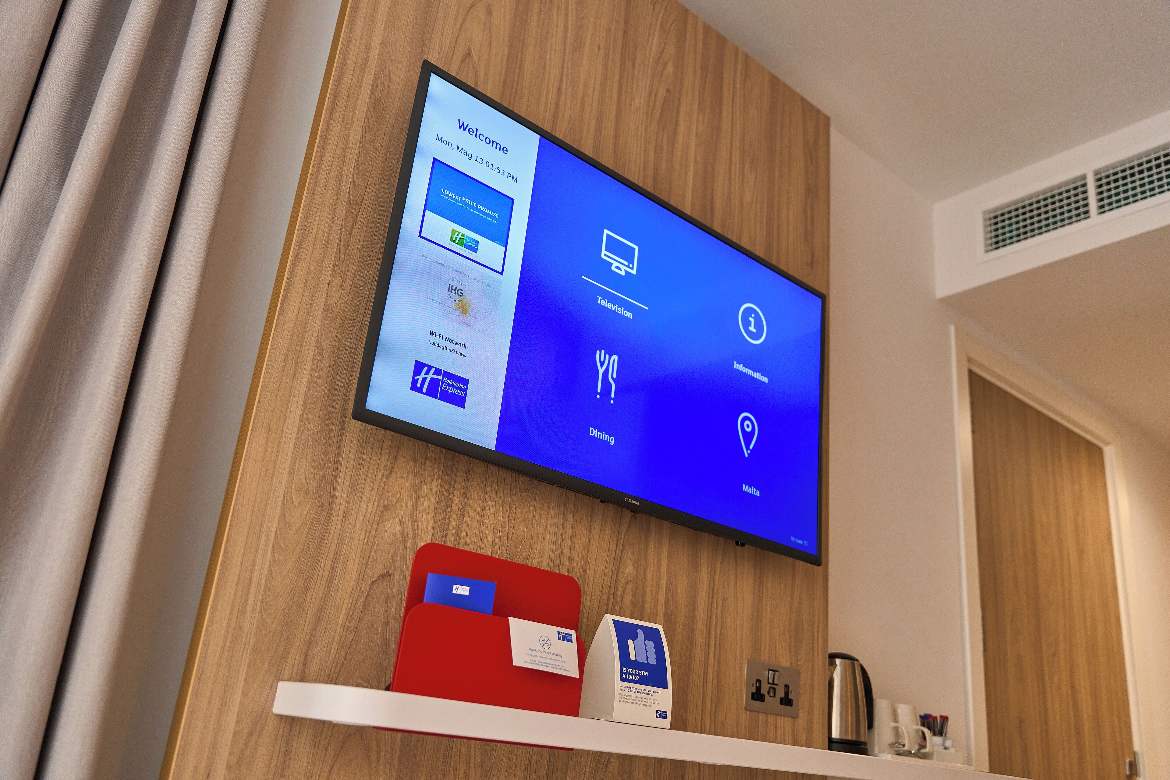 Zona de recepción de un hotel con una pantalla digital que muestra opciones de habitaciones y servicios.