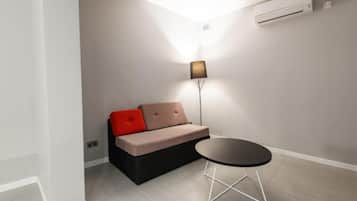 A modern room with a sofa, a small table, and a floor lamp.