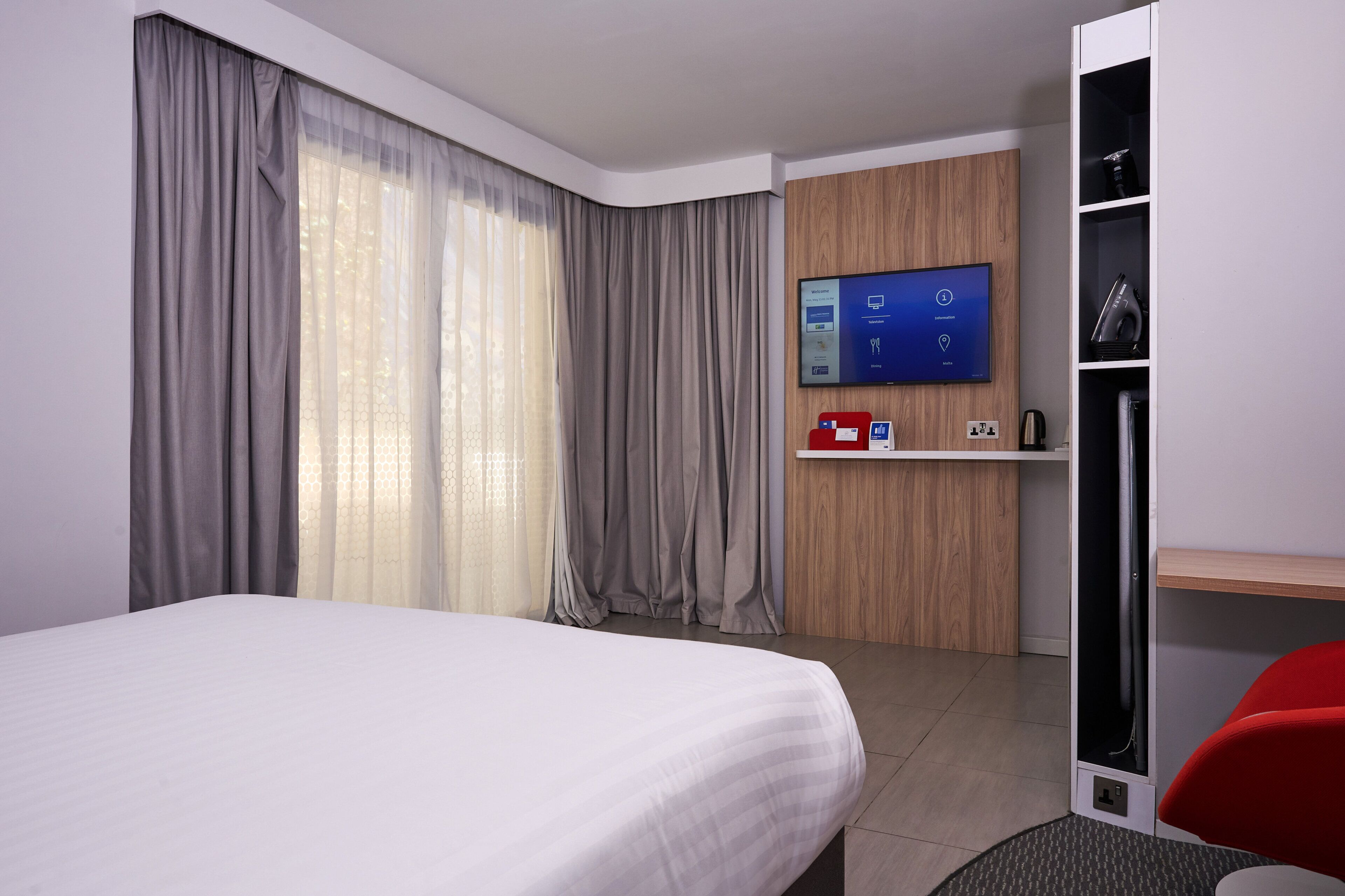 A hotel room with a bed, a desk, a TV, and a wardrobe.