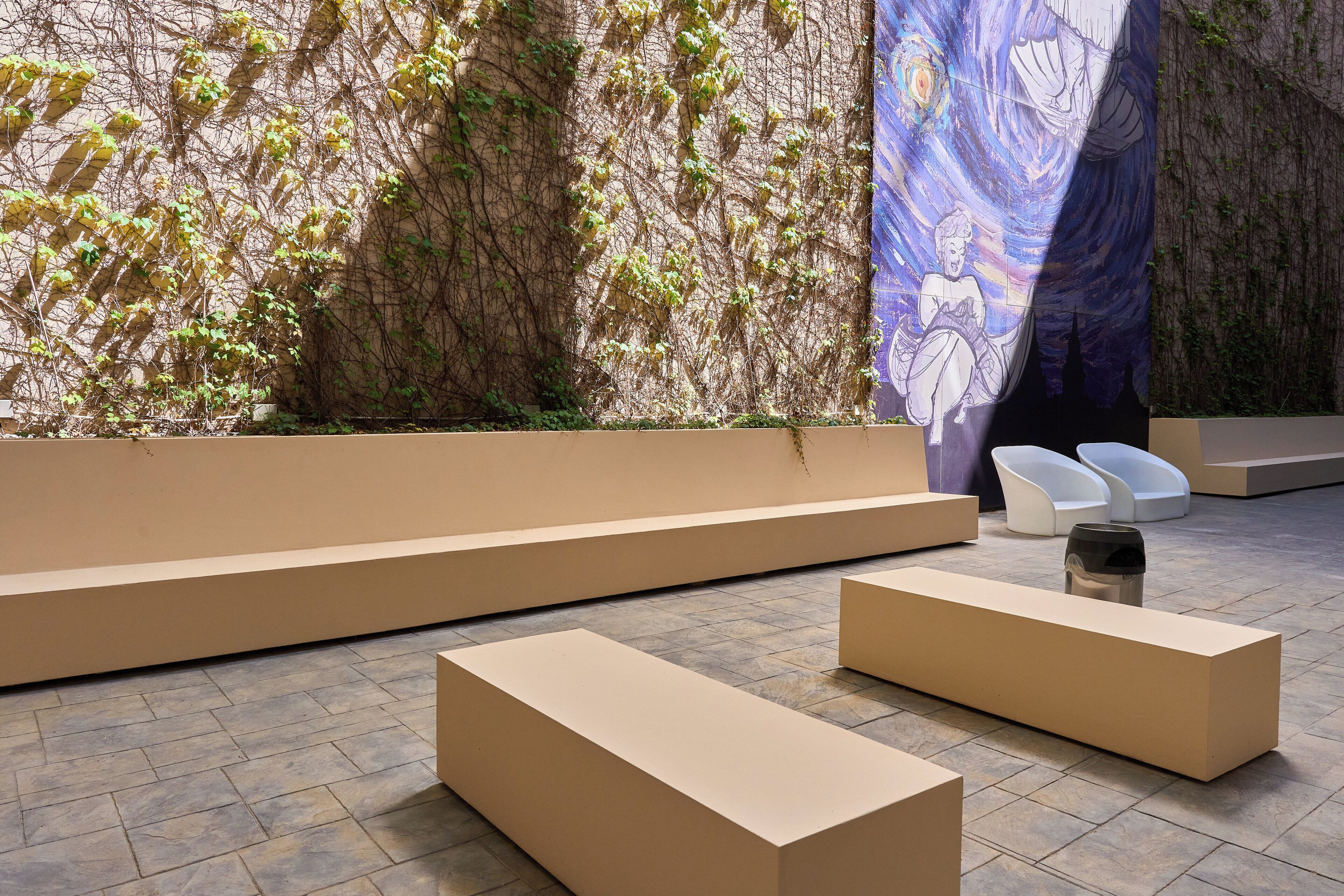 A modern interior with a seating area, a wall with climbing plants, and a large artwork.
