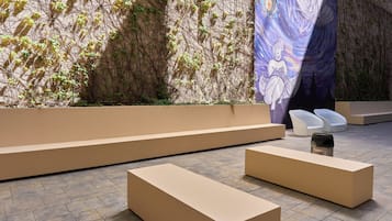 A modern interior with a seating area, a wall with climbing plants, and a large artwork.