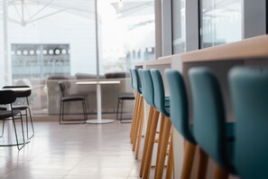 A modern dining area with wooden tables and teal chairs, large windows, and a clean, minimalist design. - Holiday Inn Express Malta by IHG (St. Julian's)