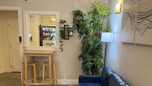 A living room with a dark leather sofa, a wooden coffee table, and a large potted plant. - Hotel Ikon (San Francisco)