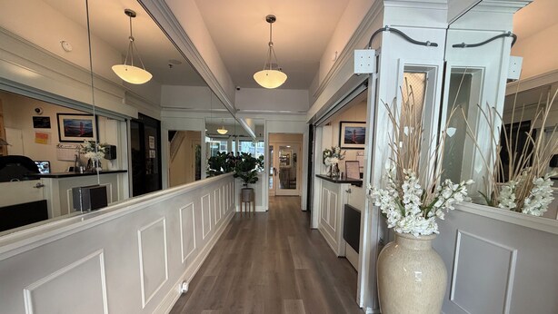 A hotel corridor with a wooden floor, white wainscoting, and pendant lighting. - Hotel Ikon (San Francisco)