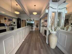 A hotel corridor with a wooden floor, white wainscoting, and pendant lighting. - Hotel Ikon (San Francisco)