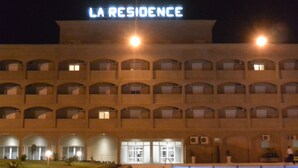 Un hotel con un letrero que dice "LA RESIDENCE" y una piscina al frente.