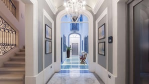 Un pasillo con candelabro, obras de arte enmarcadas y una escalera.