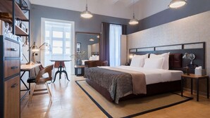 Una habitación de hotel con una cama grande, un escritorio con silla, un armario y un espejo.