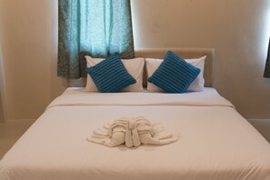 A neatly made bed with two pillows, a towel, and a headboard. - Sirin House (Krabi)