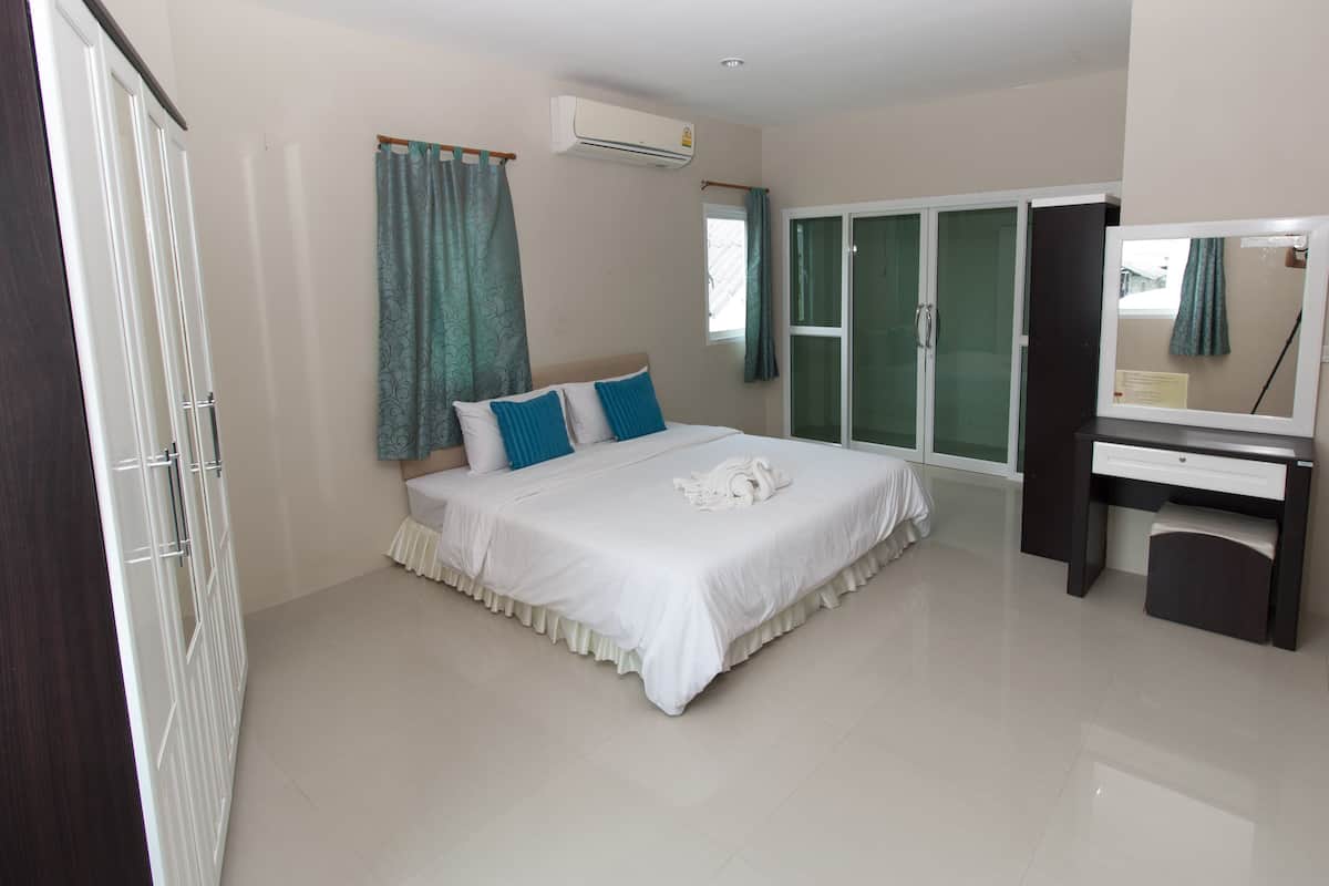 A bedroom with a bed, a desk, and a mirror.