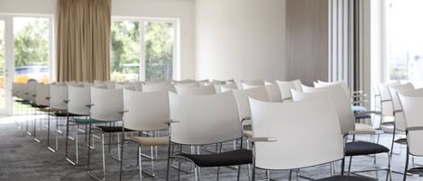 A conference room with rows of white chairs and a carpeted floor.