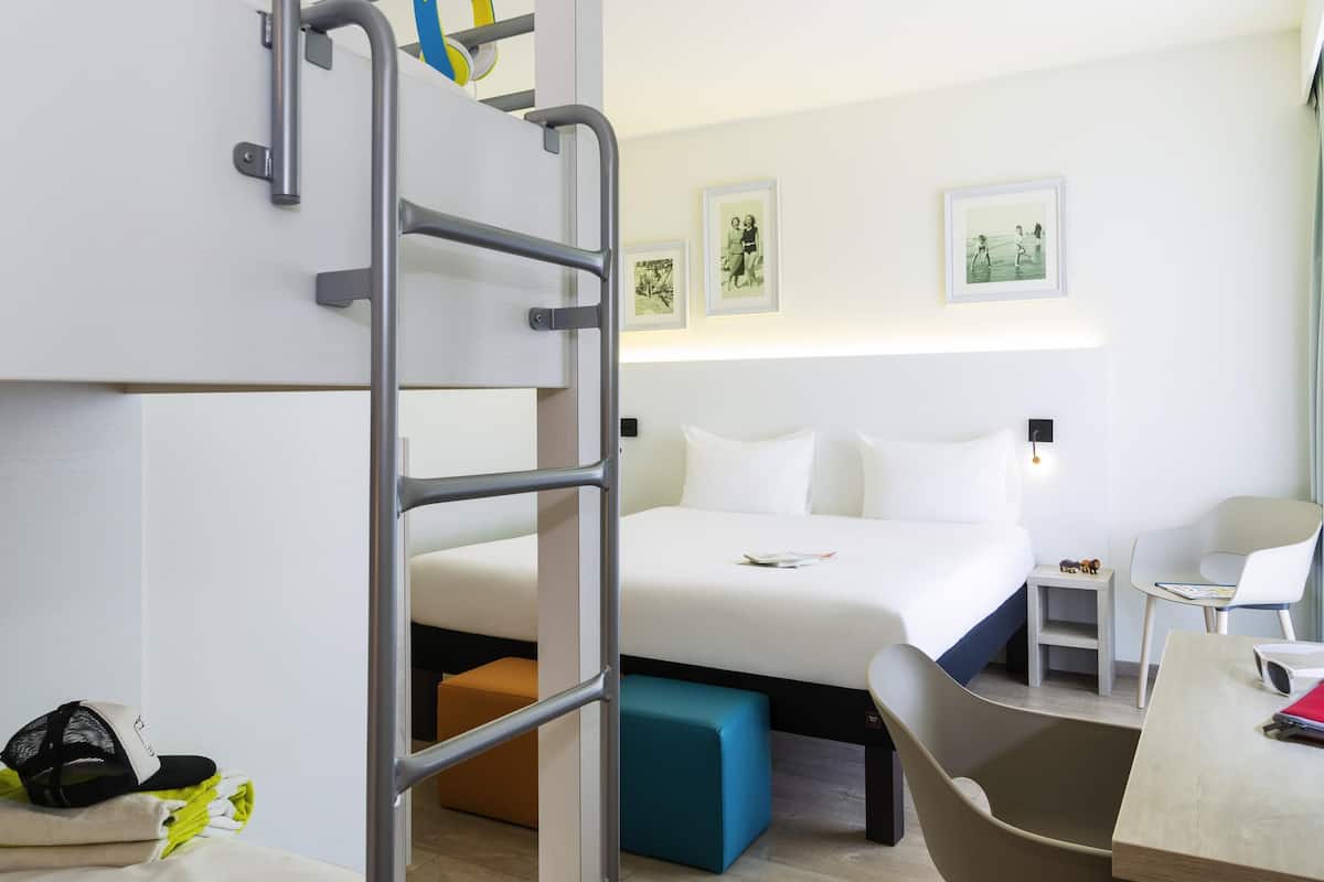 Ein Hotelzimmer mit Etagenbetten, einem Schreibtisch, einem Stuhl und einem kleinen Tisch.