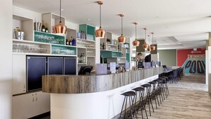 A bar area with a curved counter, multiple stools, and copper pendant lighting.