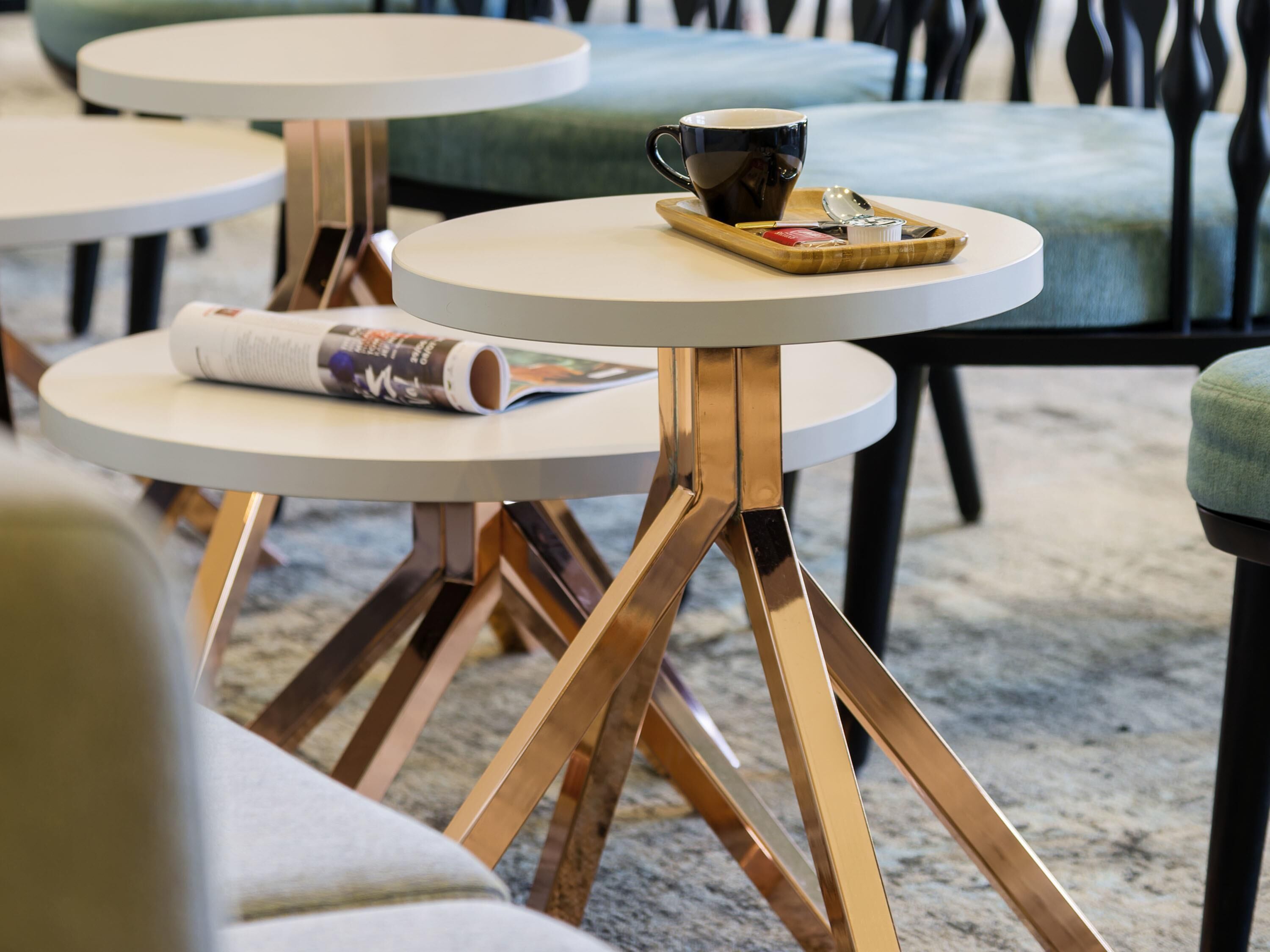 Un café moderne avec des tables rondes, une tasse de café et une cuillère sur un plateau.