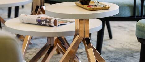 Un café moderno con mesas redondas, una taza de café y una cuchara sobre una bandeja.