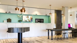 A modern reception area with a wooden floor, a round table, and bar stools.