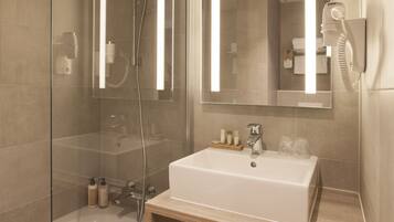 A modern bathroom with a glass-enclosed shower, a white sink, and a large mirror.
