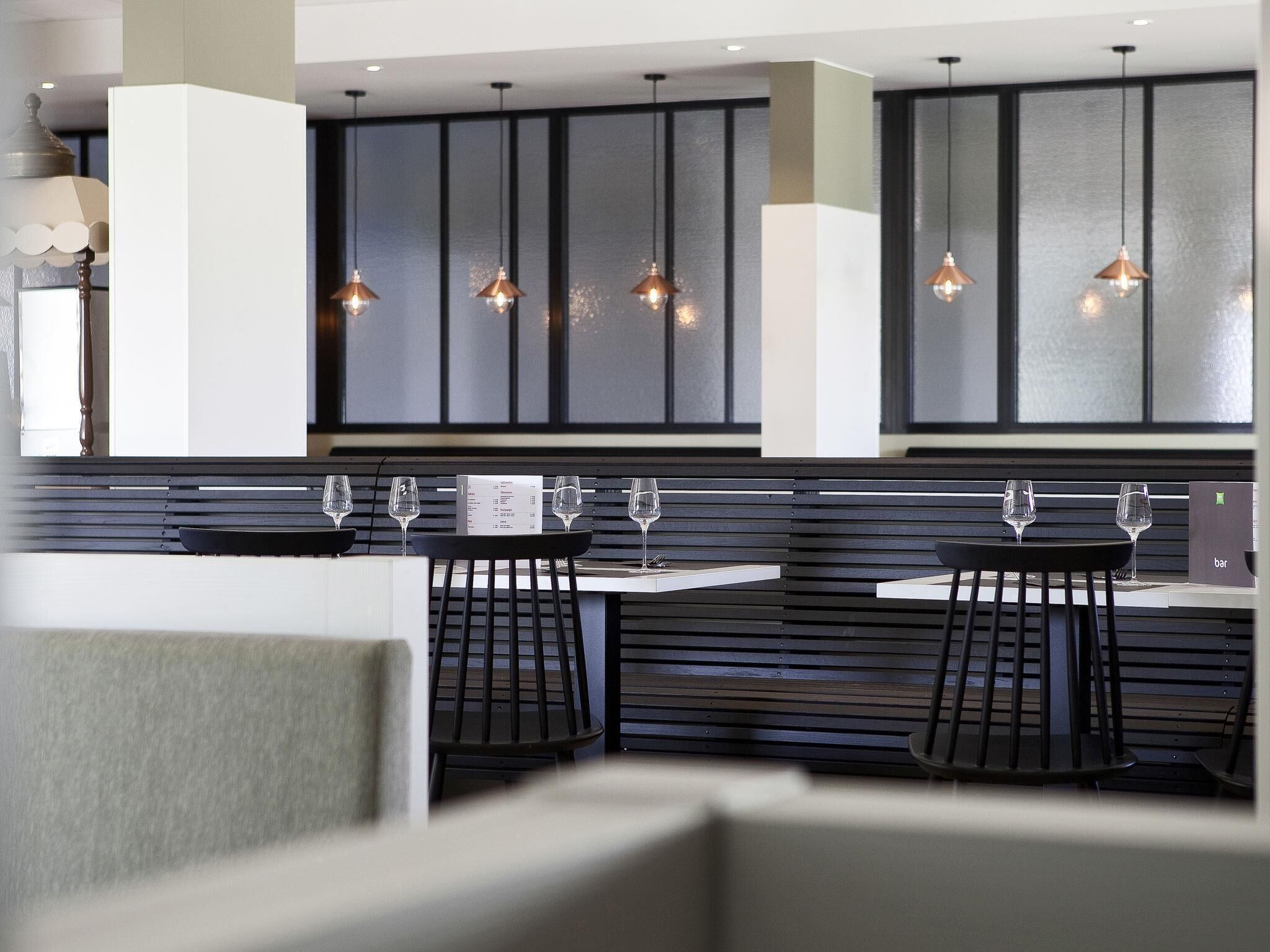 Una cocina moderna con gabinetes negros, lámparas colgantes y una zona de bar con vasos.