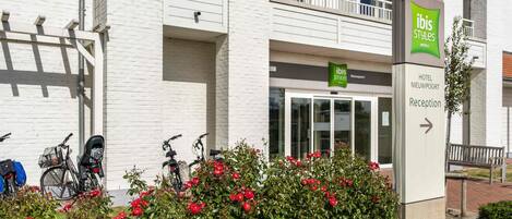 A hotel entrance with a sign for 'ibis Styles Hotel Nieuwpoort' and a reception direction sign.