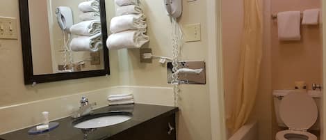 A bathroom with a sink, mirror, towel rack, hair dryer, and toilet.