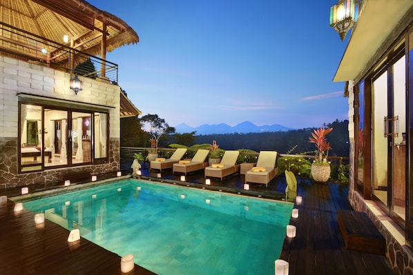 Un área de piscina con sillas de descanso y vistas a montañas.