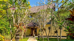 A pathway leading to a building surrounded by lush greenery and a stone lantern. - Hillside Eden Bali (Payangan)