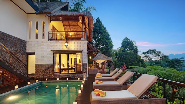 A two-story building with a swimming pool, lounge chairs, and a thatched-roof structure. - Hillside Eden Bali (Payangan)