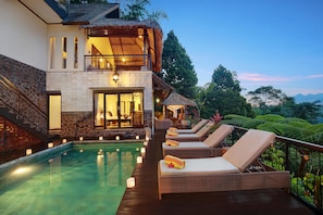 A two-story building with a swimming pool, lounge chairs, and a thatched-roof structure. - Hillside Eden Bali (Payangan)
