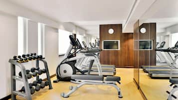 A modern gym with treadmills, elliptical machines, and a dumbbell rack.
