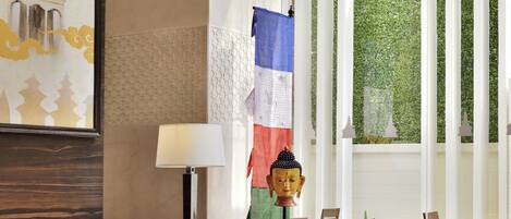 A modern hotel lobby with a sofa, armchairs, a coffee table, and a Buddha head sculpture.