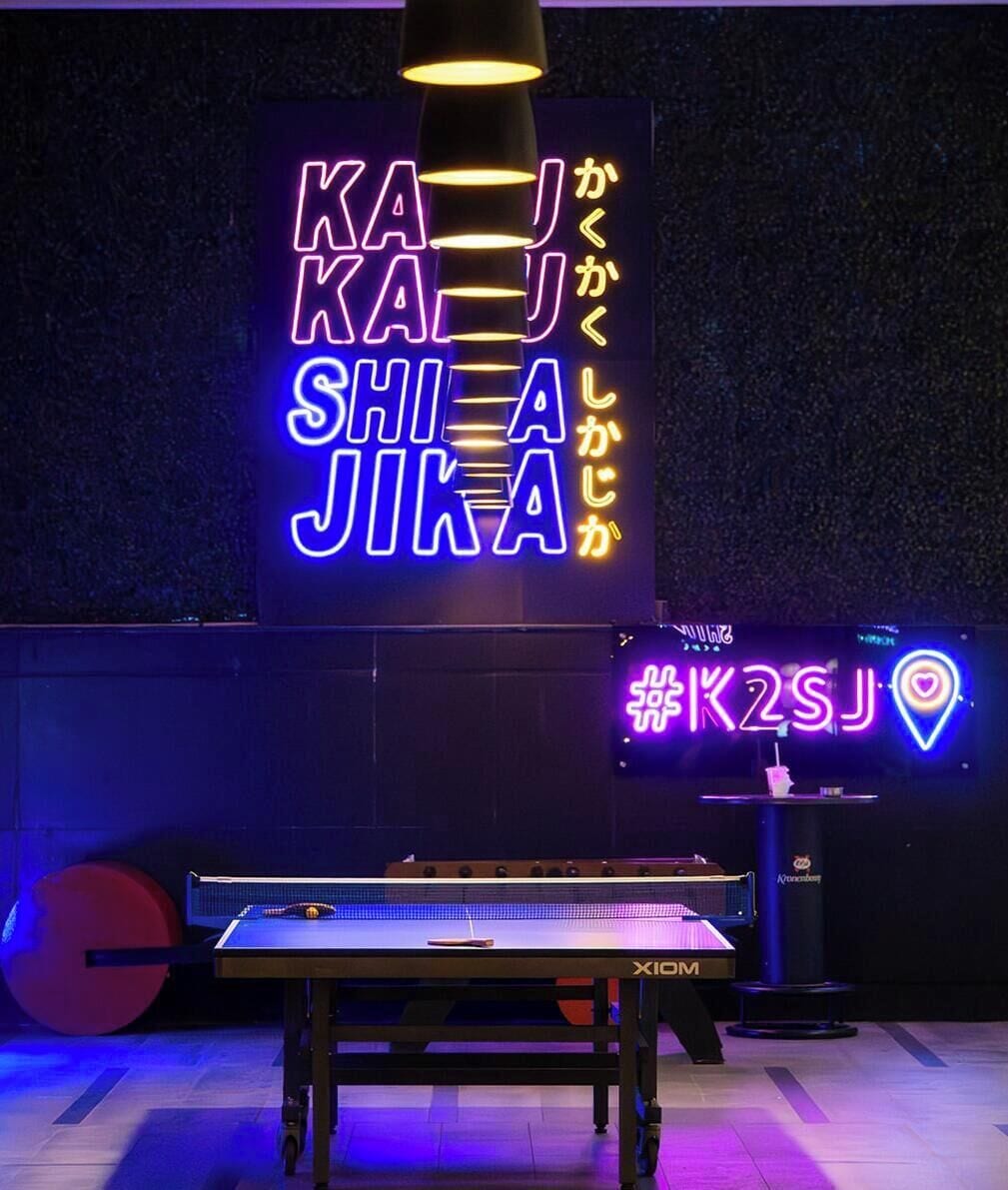 Une table de ping-pong surmontée d’un panneau lumineux au néon.
