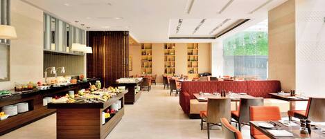 Een modern restaurant met een buffet, een zithoek en uitzicht op groen.