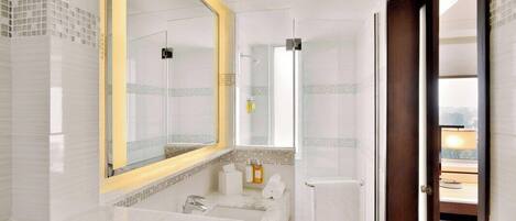 Un baño moderno con un espejo grande, una ducha y un tocador con lavabo.