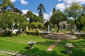 A well-manicured garden with a central circular fountain, surrounded by a variety of trees and a classical building in the background. - Fairfield by Marriott® Kathmandu Thamel (Kathmandu)