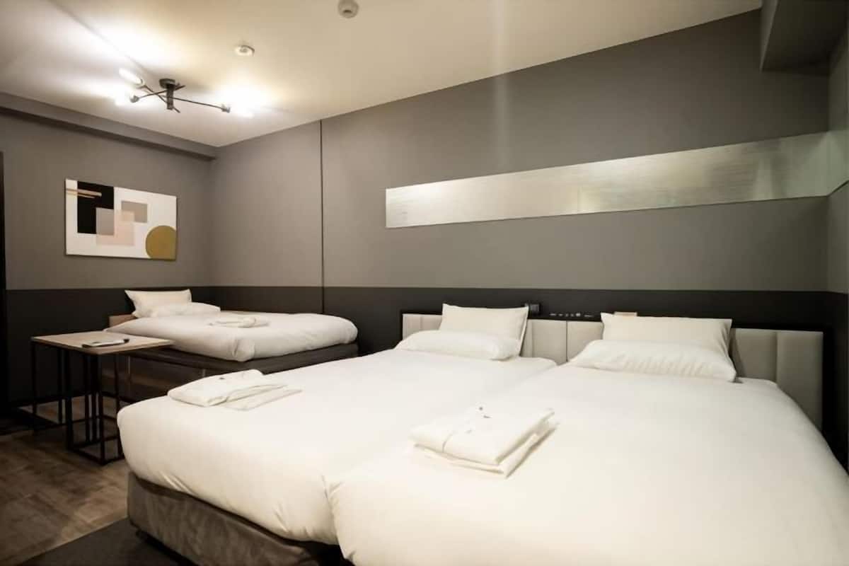 A hotel room with two beds, a desk, and a modern ceiling light fixture.