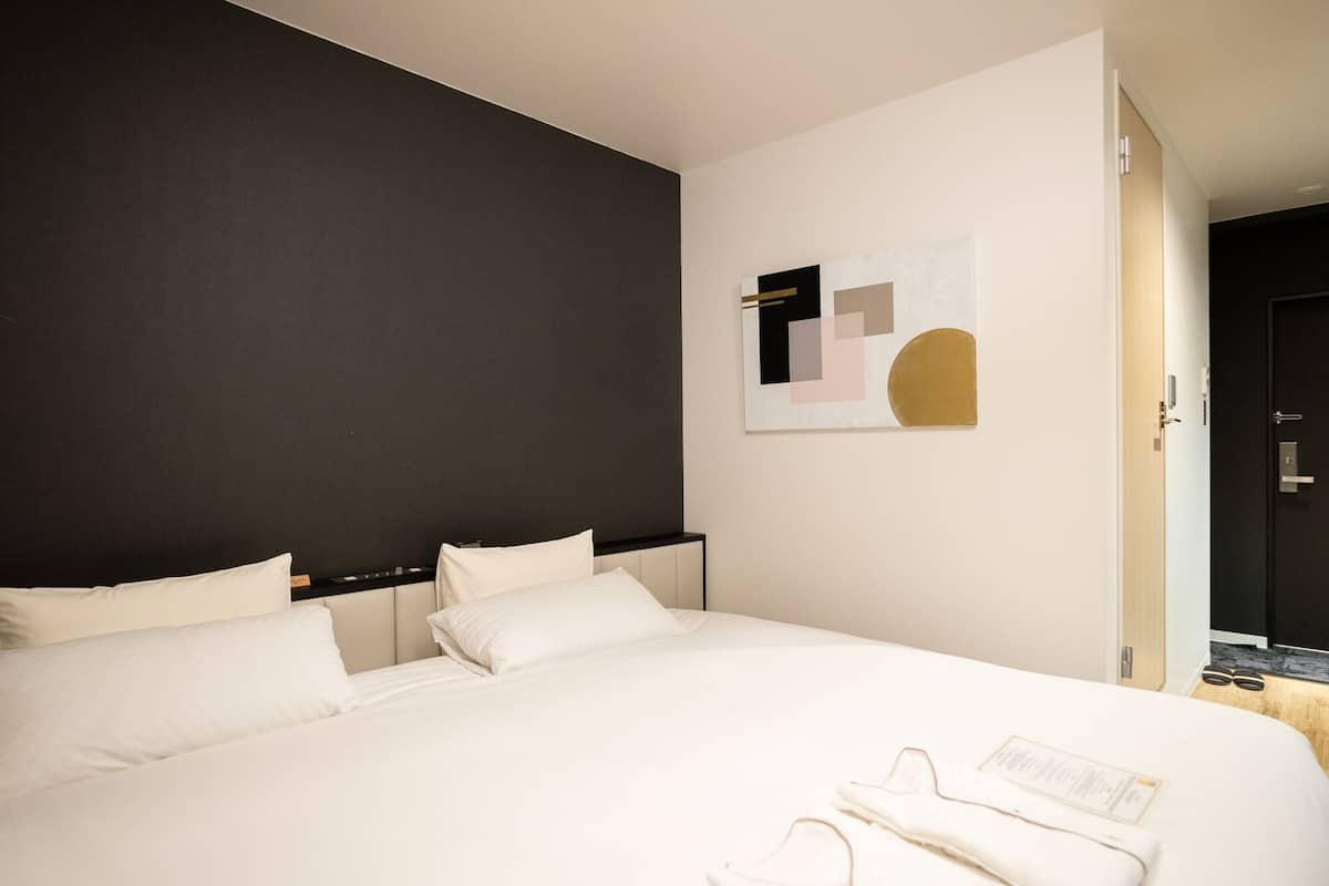A hotel room with a large bed, a dark accent wall, and a modern abstract painting.