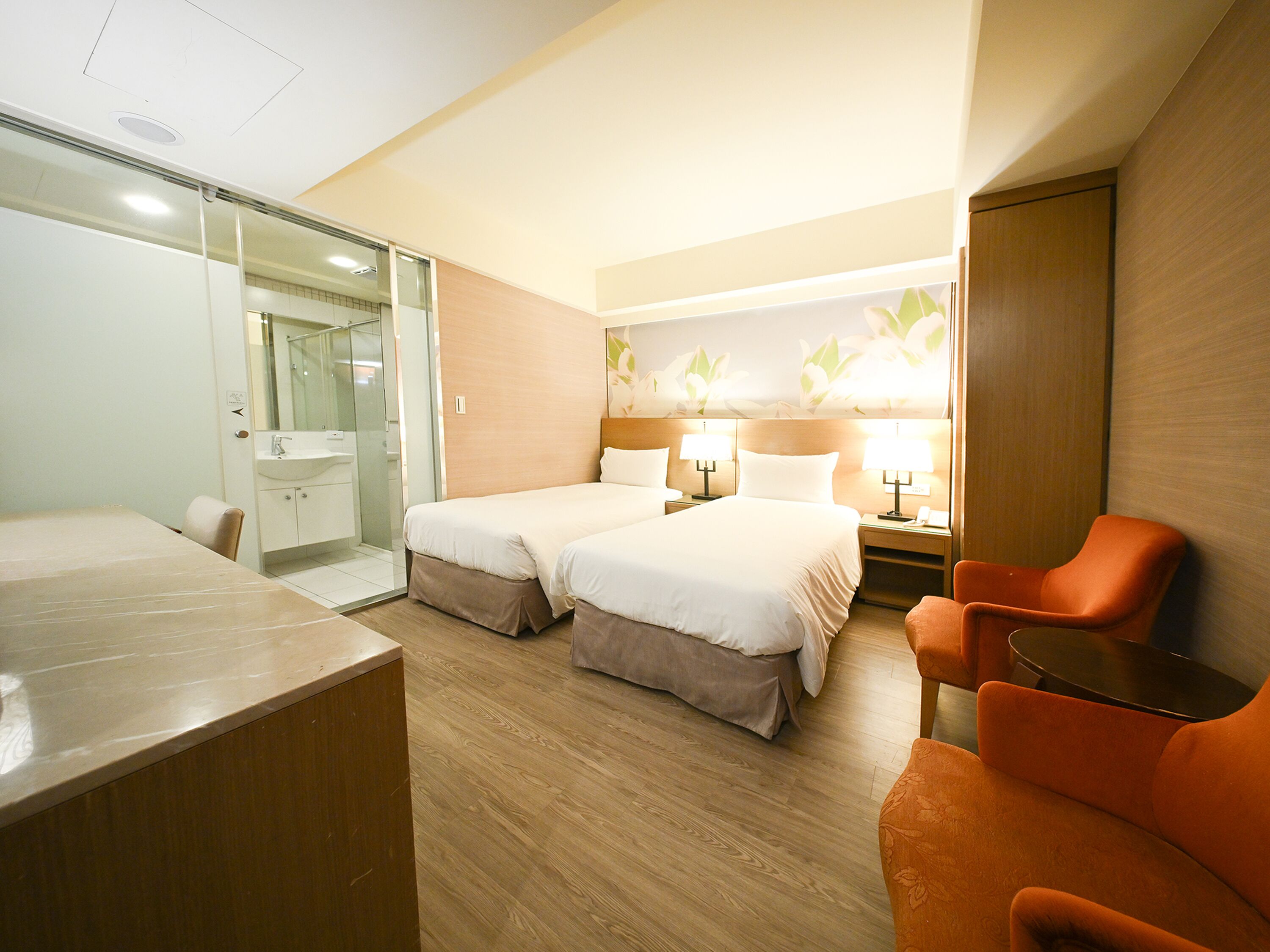 Una habitación de hotel con dos camas, un baño, un escritorio y una silla.